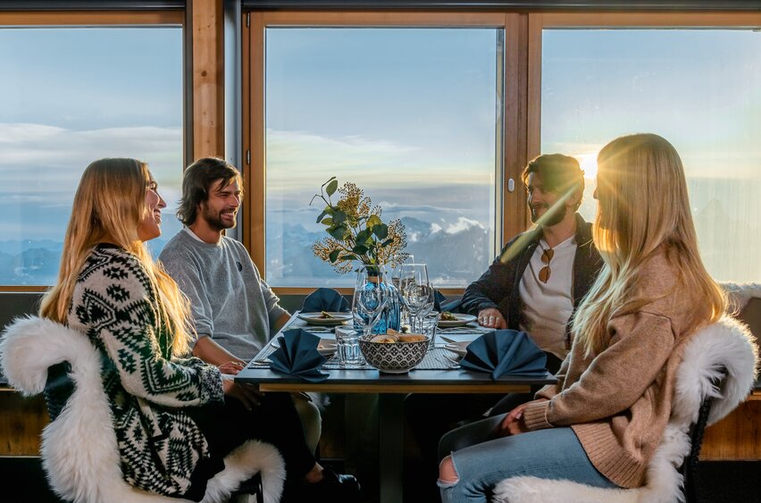 Two couples sitting at the table of the Glacier Paradise Restaurant at sunset | © Basic Home Production