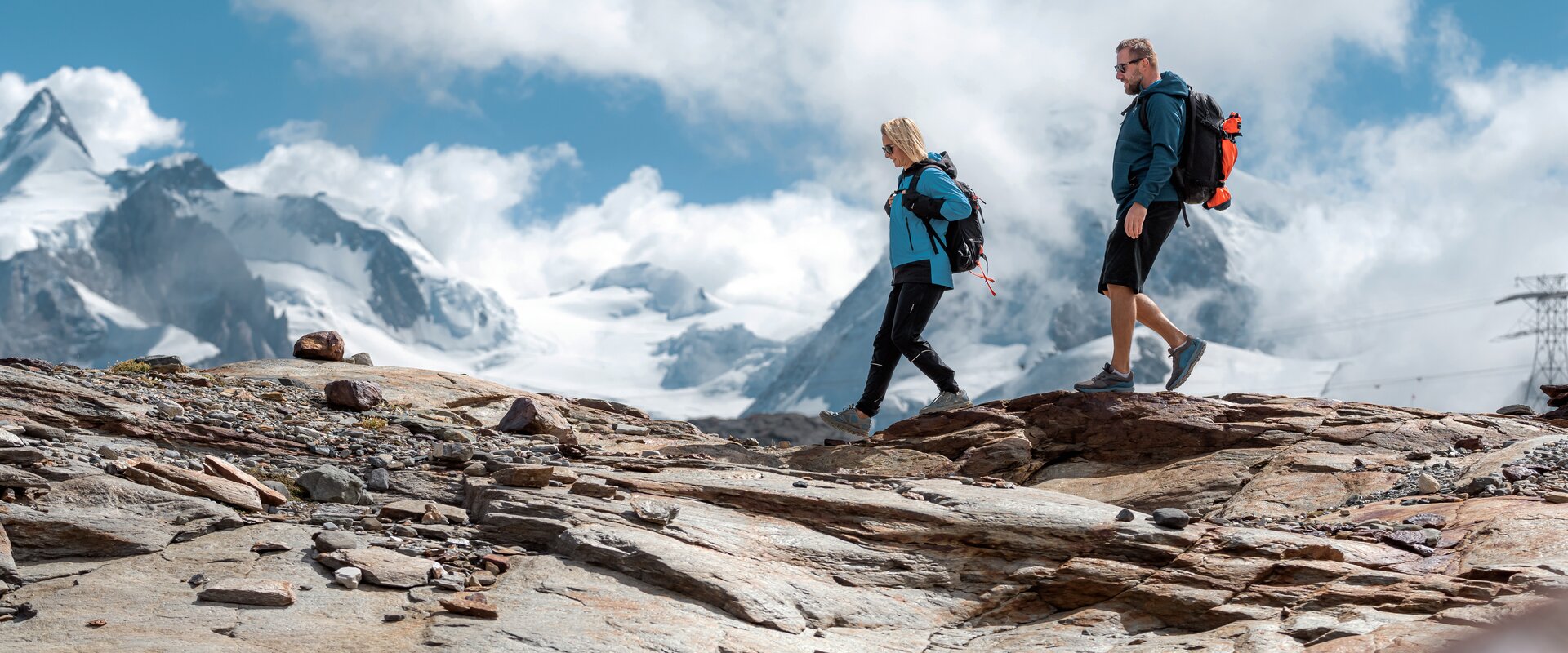 Matterhorn Glacier Trail | © basic_home Zwei Personen wandern über Felsen, im Hintergrund die Zermatter Bergwelt | © basic_home