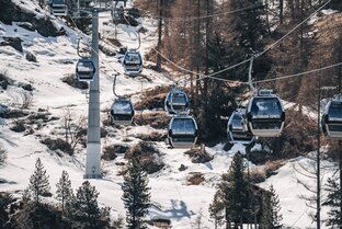 Die Aneinanderreihung der fahrenden Gondel zeigt silbrige und blaue Kabinen | © Gabriel Perren 